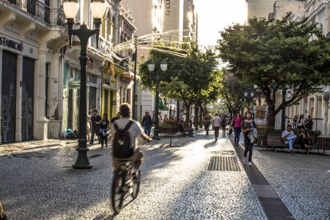 Man biking down cobbled road of pedestrians 