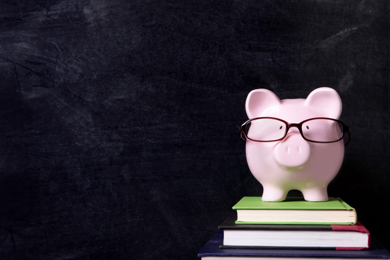 a cute, pink, piggy bank wearing black rimmed glasses and standing on three books