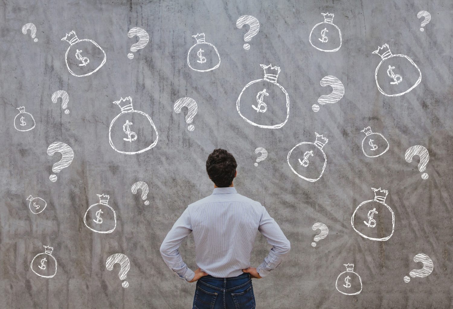 a man stands, hands on hips, staring at a wall painted with question marks and bags full of money