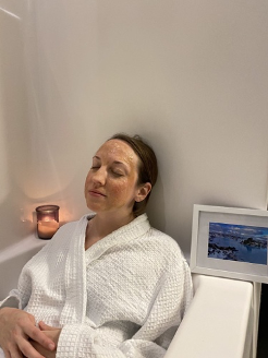 Woman wearing white bathrobe with face mask
