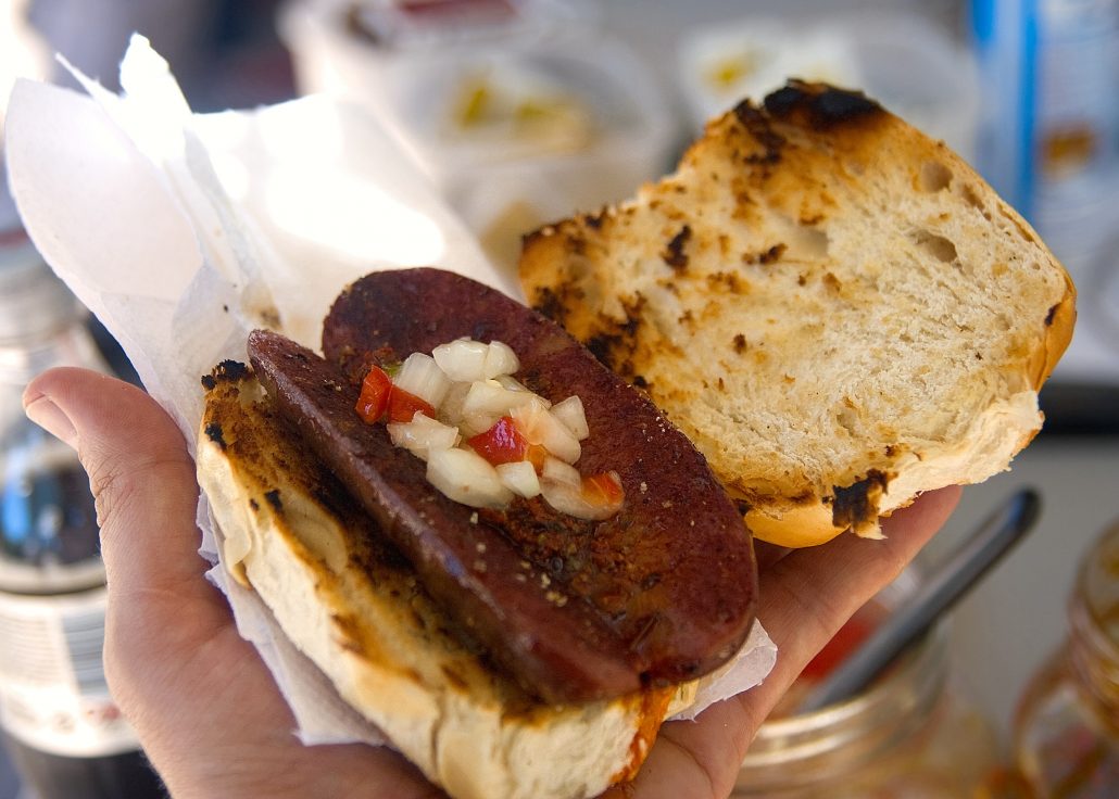 Choripan sandwich - chorizo split down middle and places on roll, topped with chimichurri 